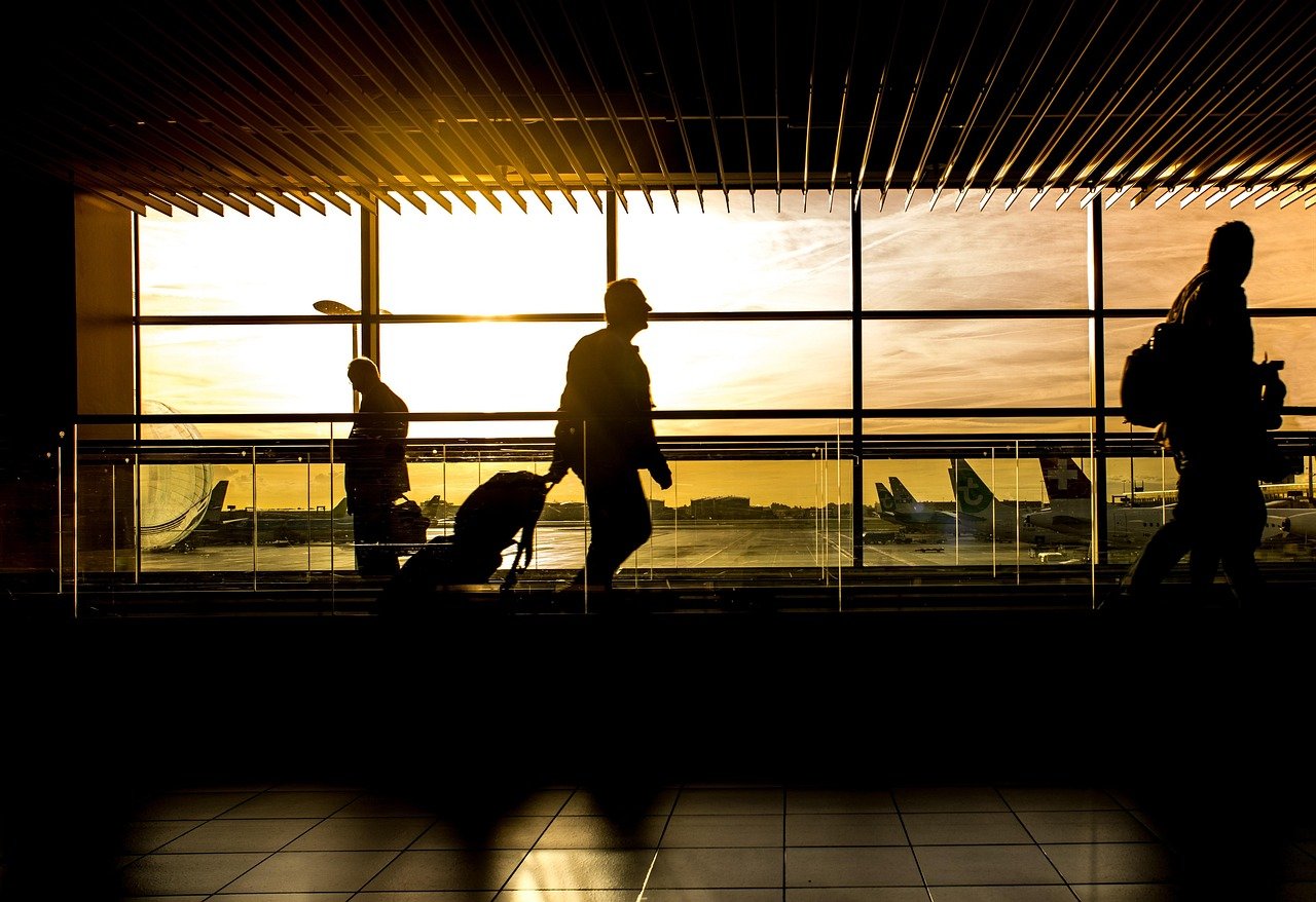 Airport terminal interior with travellers walking toward departure gates