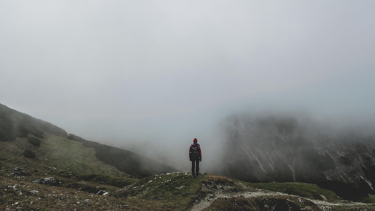 Hiker on a misty highland trail in a foggy mountain landscape