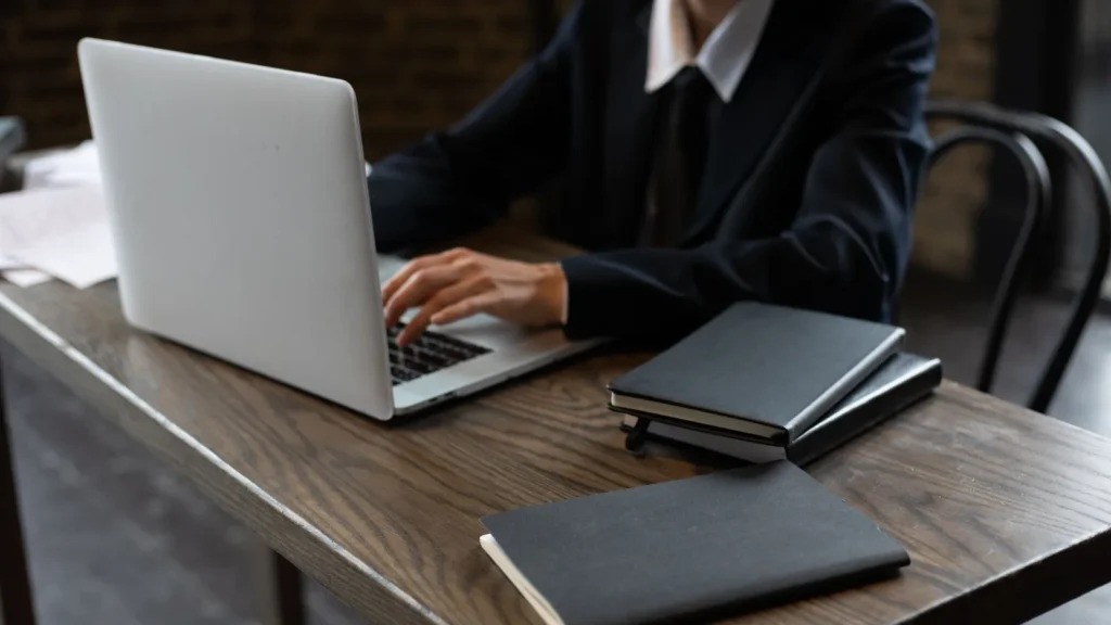 Business traveller in a suit typing on a laptop at a wooden table