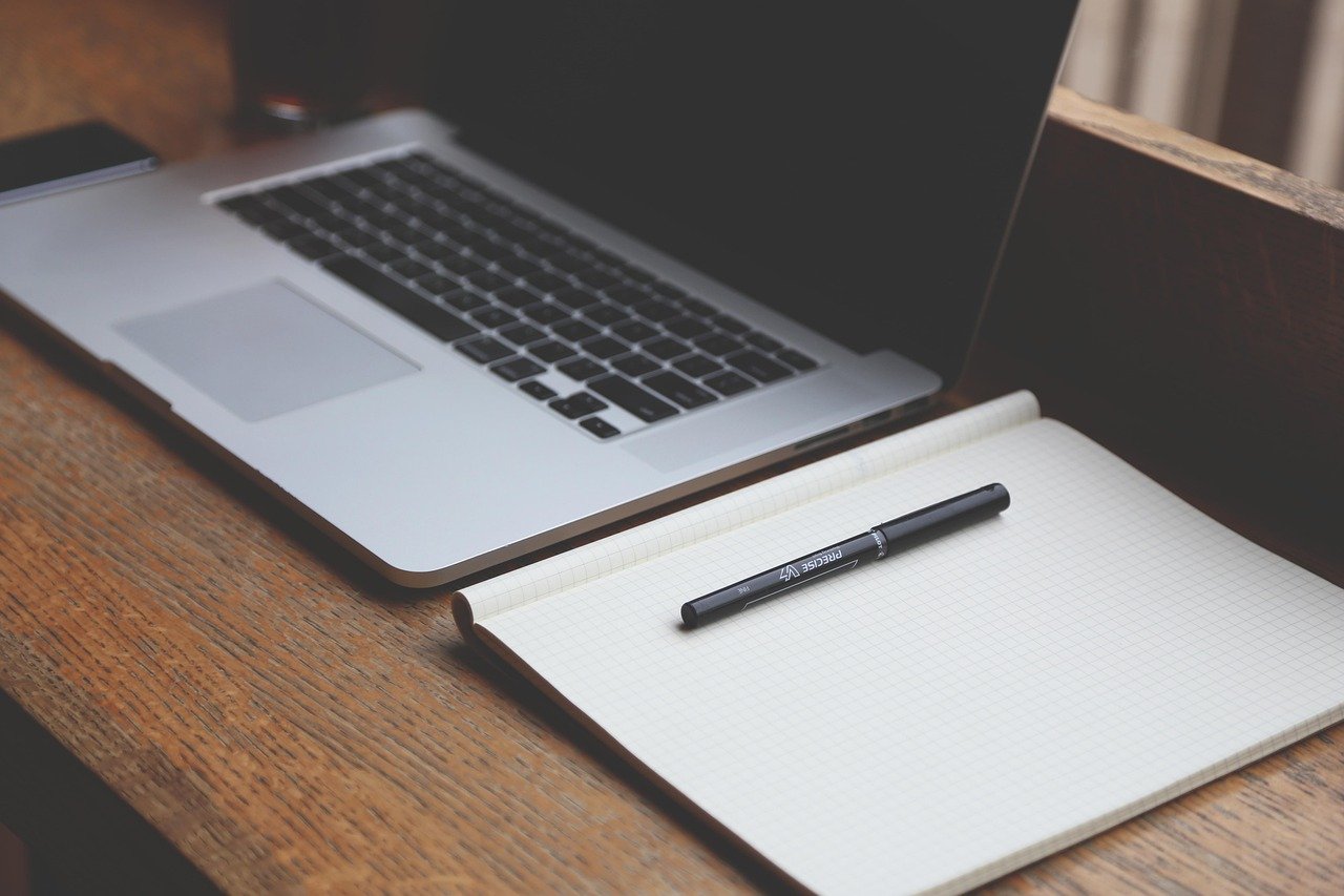 Desk workspace with a laptop, notebook and pen used for billing administration