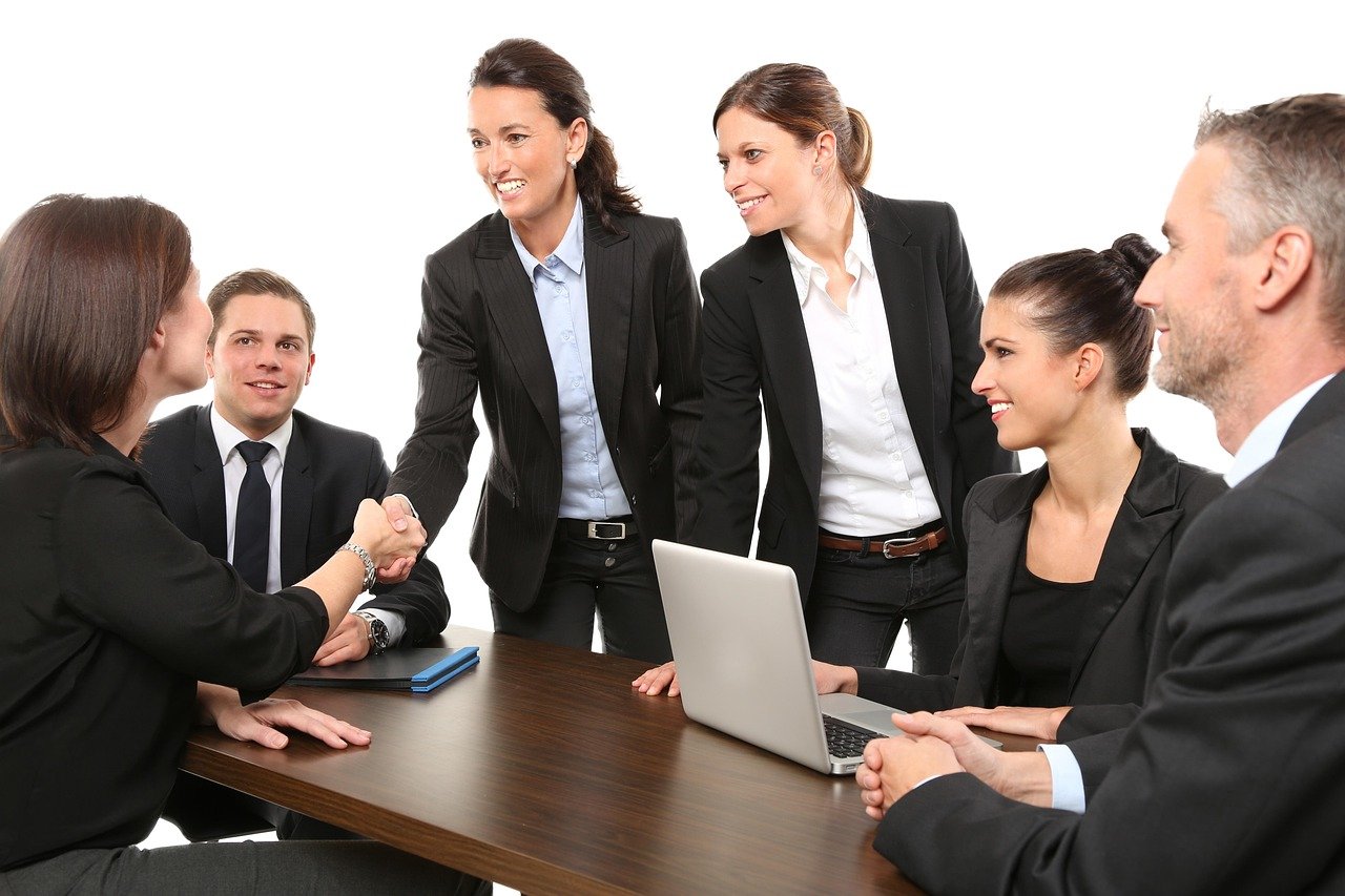Business professionals in formal attire shaking hands in a Saudi office meeting