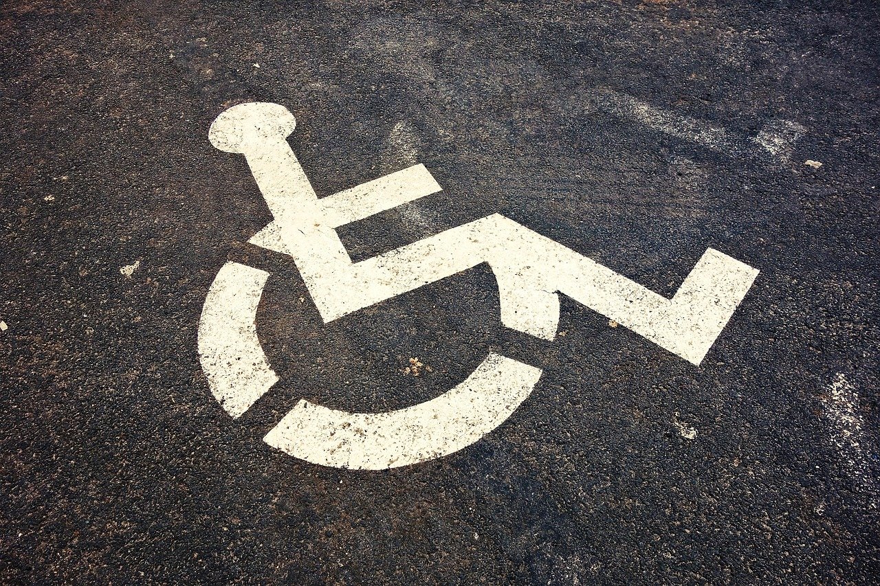 Driver assisting a traveller with a wheelchair at an airport arrivals pickup point