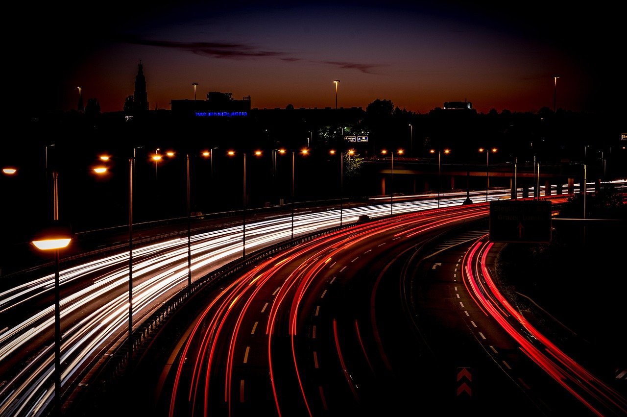 Car travelling along a lit city highway at night on the way to a hotel