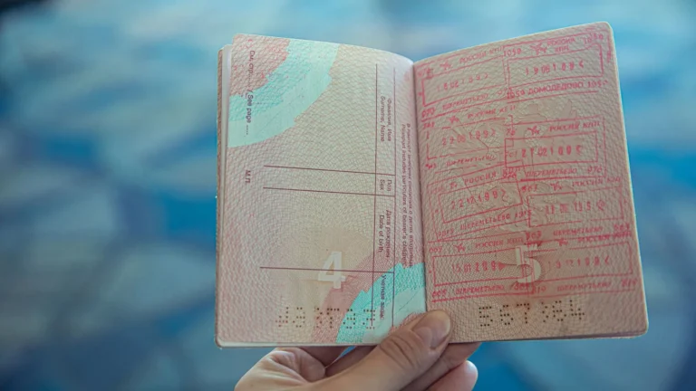 Hand holding an open passport showing visa stamps