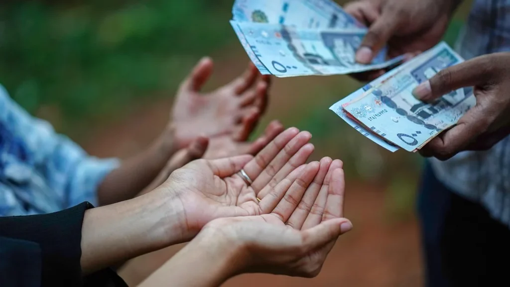 Saudi riyal banknotes being handed from one person to another