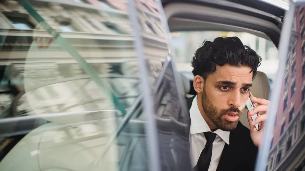 Businessman in a suit talking on his phone from the back seat of a car