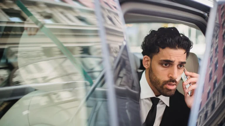 Businessman in a suit talking on his phone from the back seat of a car