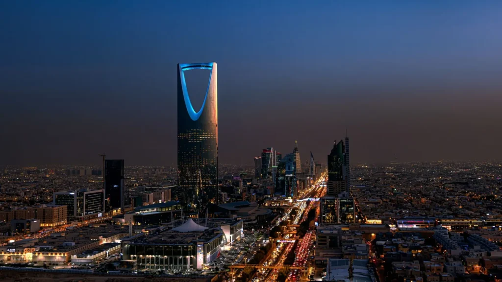 Vista nocturna de Riad con la torre Kingdom Centre iluminada: las horas de la tarde y la noche, cuando más ayuda el transporte reservado a quien viaja solo por trabajo