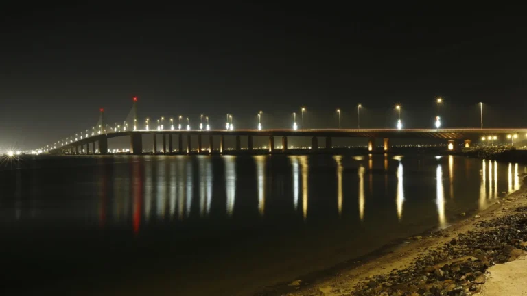 Illuminated bridge reflected in calm water at night