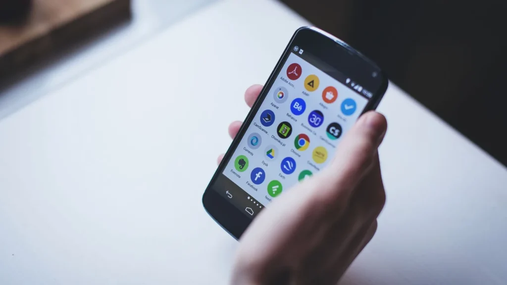 Hand holding a smartphone with apps on the screen